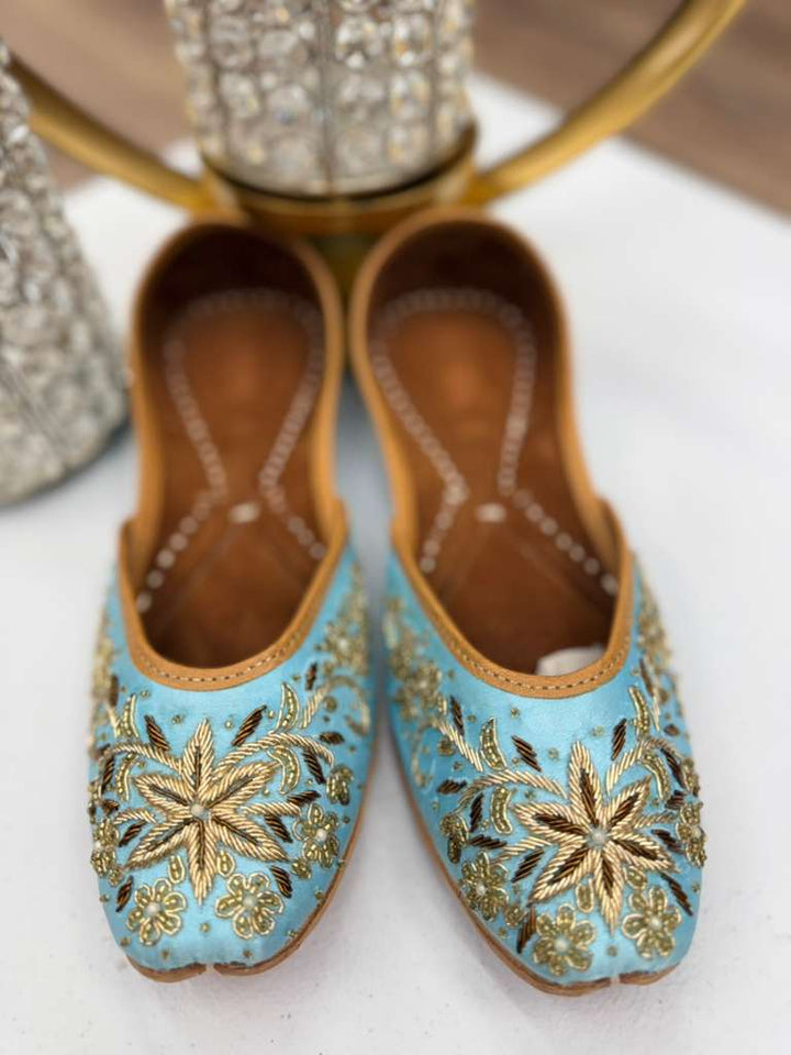 Bisma Light Blue Jutti - Blue Khussa with intricate gold embroidery on light blue fabric, handcrafted ethnic flats for festive wear.