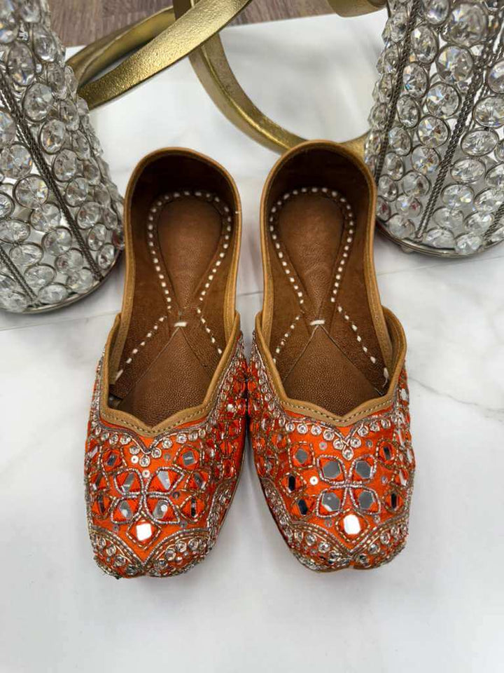 Sharmila Orange Jutti - Timeless Footwear featuring vibrant orange fabric and detailed embellishments. Ideal for ethnic and formal occasions.