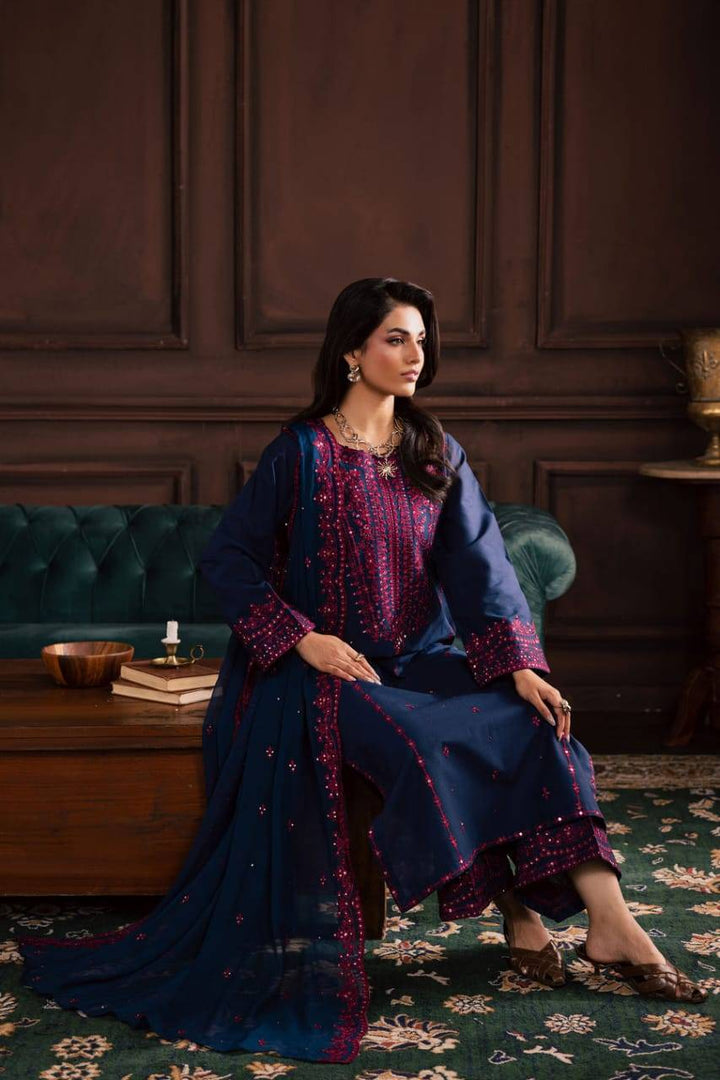 Model sitting in BATIK Lamia 3Pc navy embroidered khaddar outfit, styled with matching dupatta and traditional accessories for festive wear.
