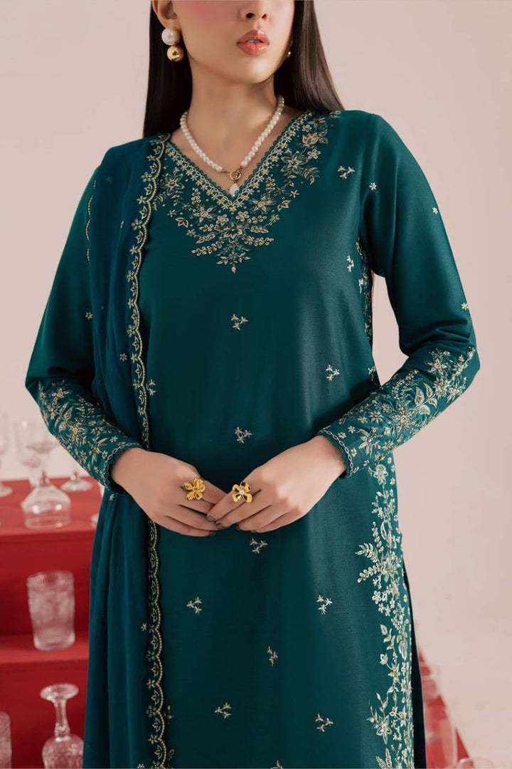 Zoomed-in view of BATIK Dark Forest Dress - PAKISTANI BATIK WOMEN DRESS ONLINE showing fine embroidery on teal khaddar fabric and gold accessories.