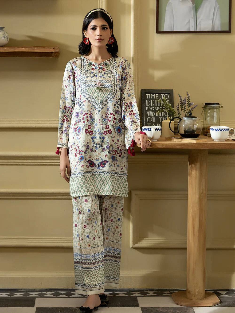 Close-up of Rangreza silk 2-piece outfit with detailed floral and geometric print, tassel accents, and red tassel earrings