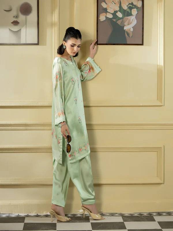 Woman in silk 2-piece with floral embroidery, holding sunglasses indoors