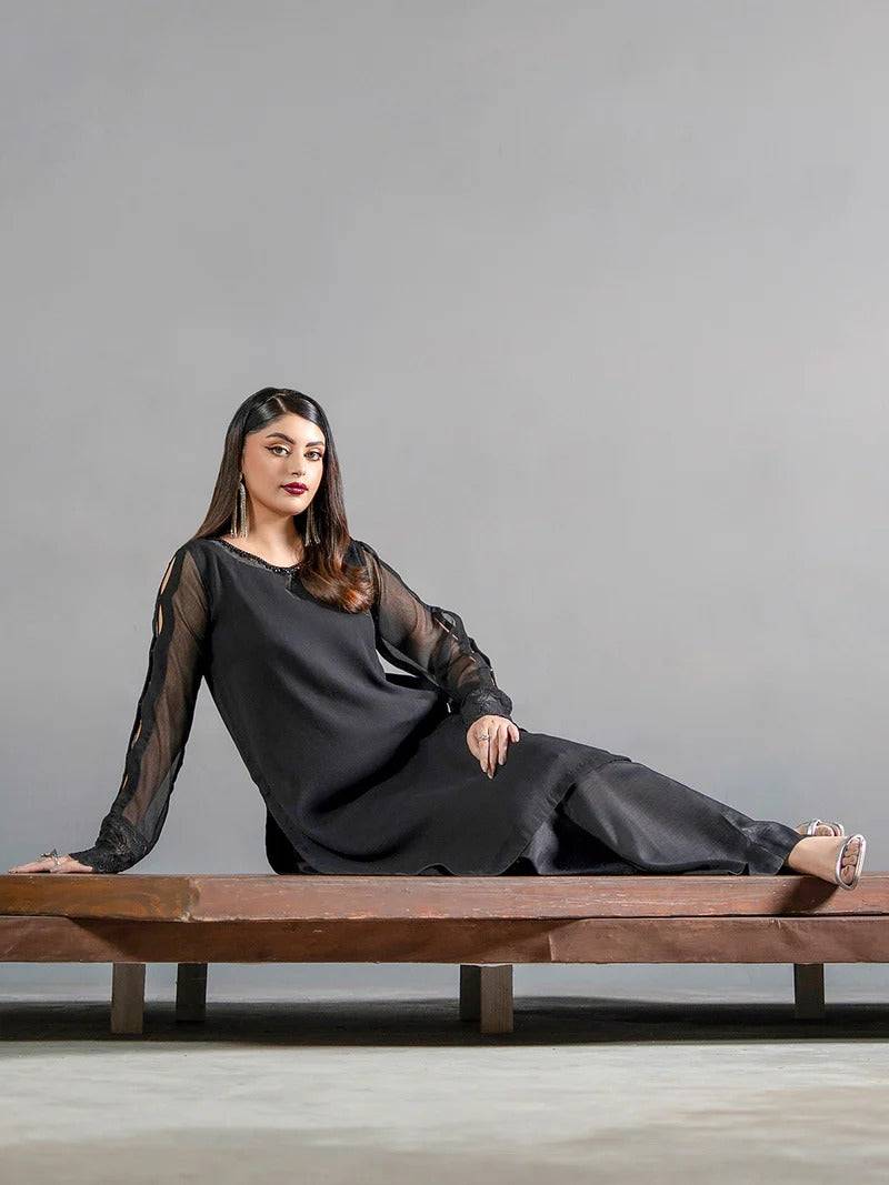 Close-up of woman wearing black chiffon kurta with cutout sleeves and earrings
