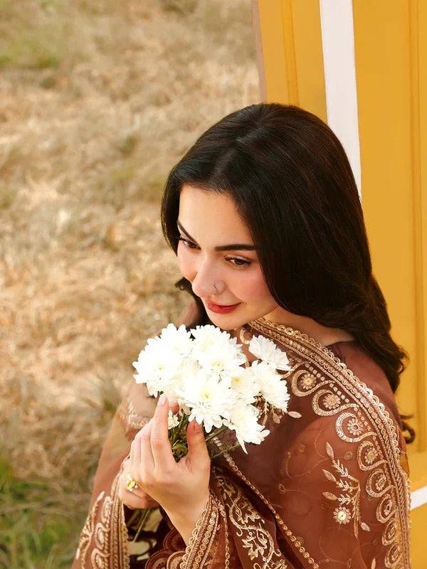 Woman holding white flowers in RANGREZA JANAN CINNAMON embroidered sharara suit