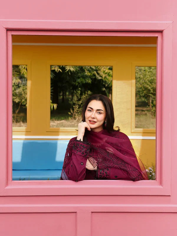 Model sitting on yellow bench with maroon kurta and floral garden background