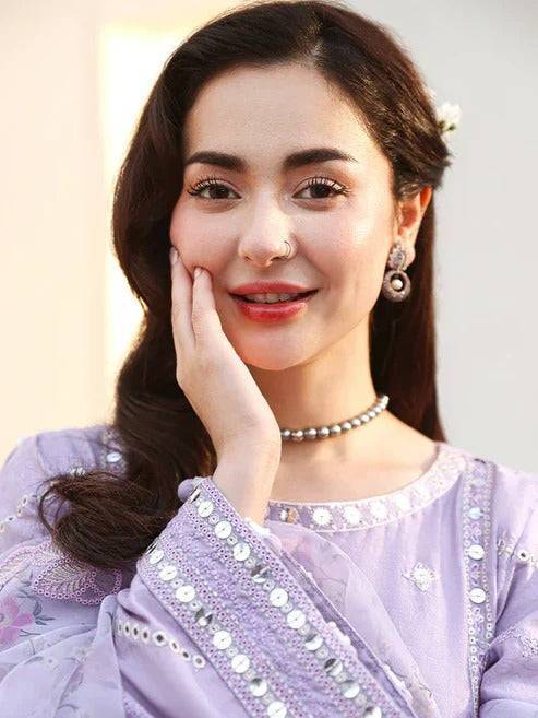 Woman in lilac embroidered traditional dress with dupatta, jewelry, and floral background