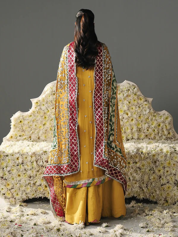 Back view of yellow embroidered dress with red and green dupatta, floral backdrop