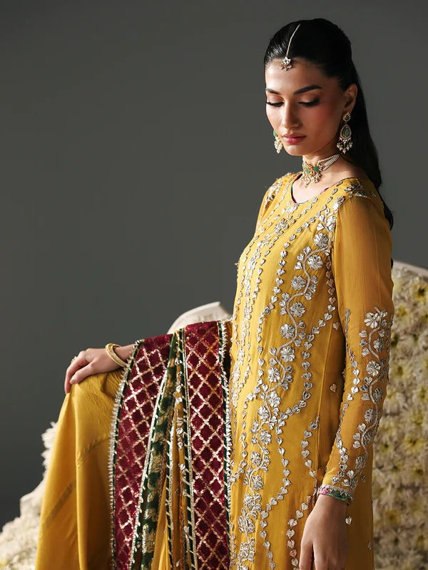 Close-up of woman in yellow embroidered dress with jewelry, floral background