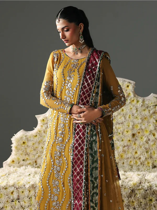 Full-length woman in yellow embroidered dress with jewelry, floral background