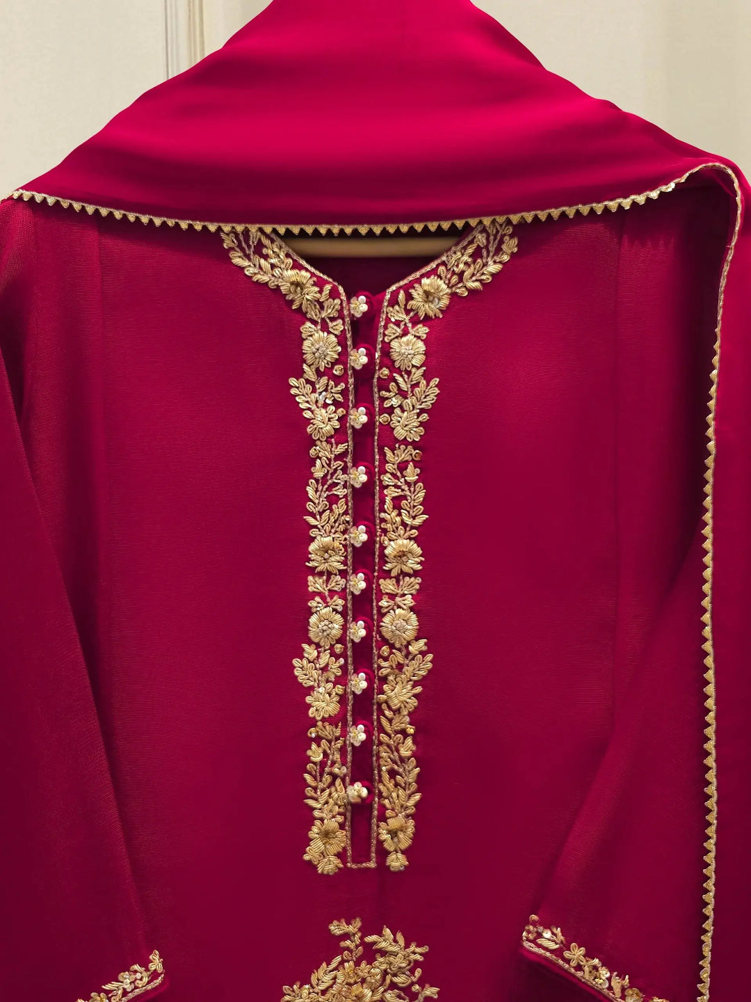 Close-up of AGHA NOOR embroidered neckline featuring intricate gold floral threadwork on cotton net fabric for elegant Pakistani fashion.