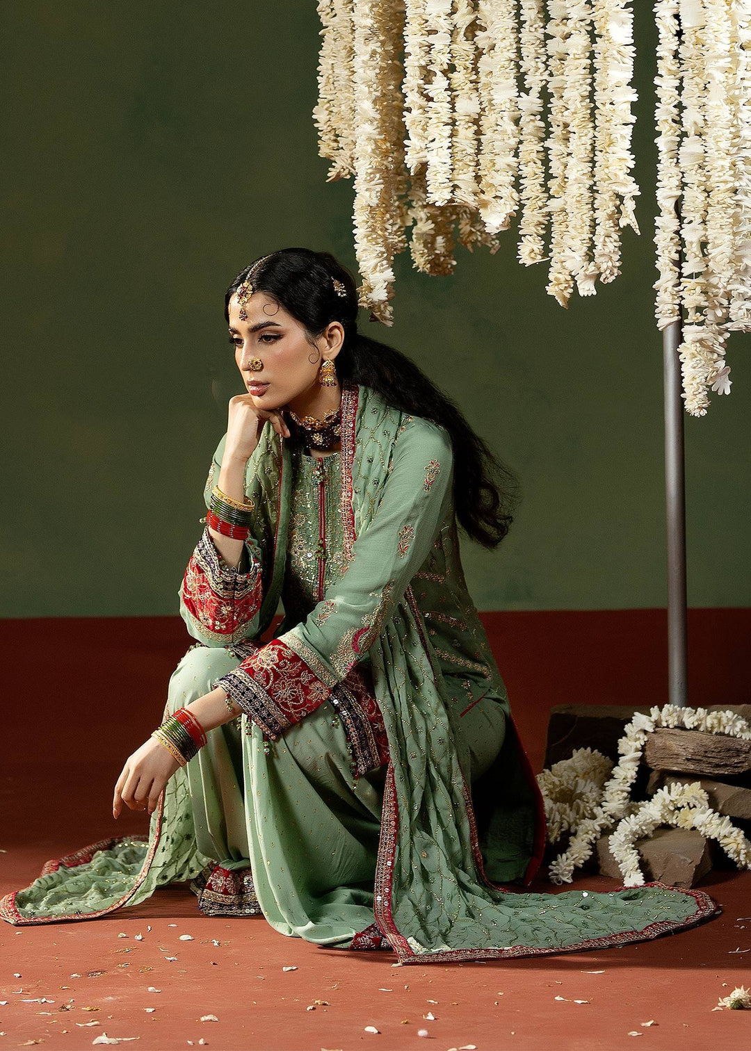 Model seated in RANGREZA PISTACHIO M-913-13 formal Pakistani outfit featuring embroidered chiffon fabric with velvet borders and elegant styling.