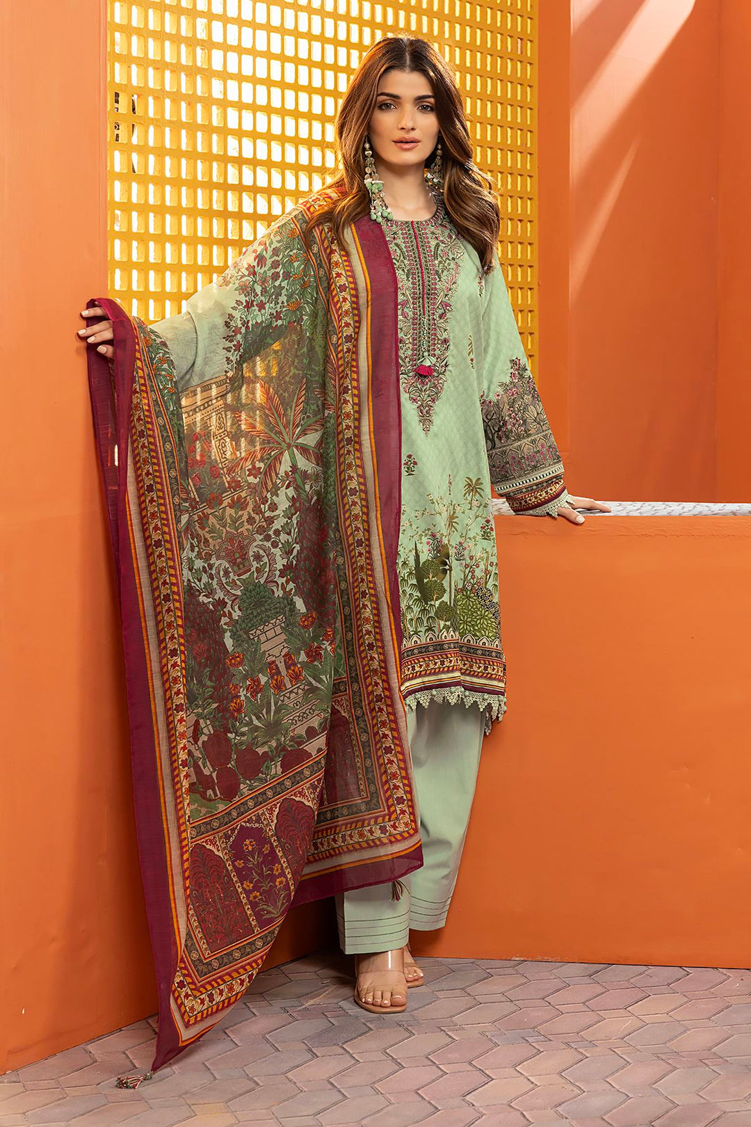 shop pakistani dresses online a woman standing in front of a wall wearing a green and maroon dress