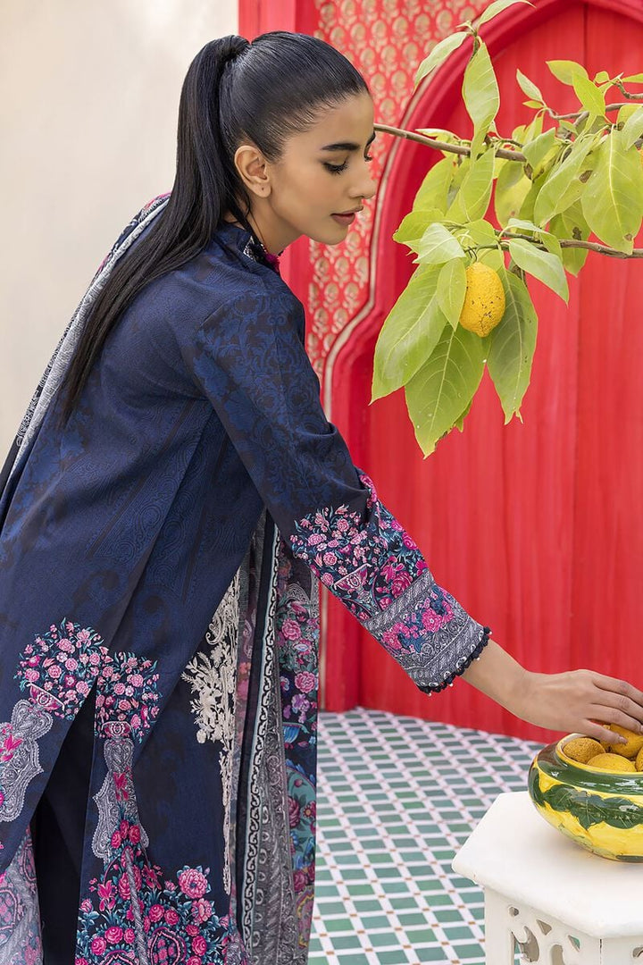 Pakistani Branded Clothes a woman standing in front of a table with a bowl of fruit on it