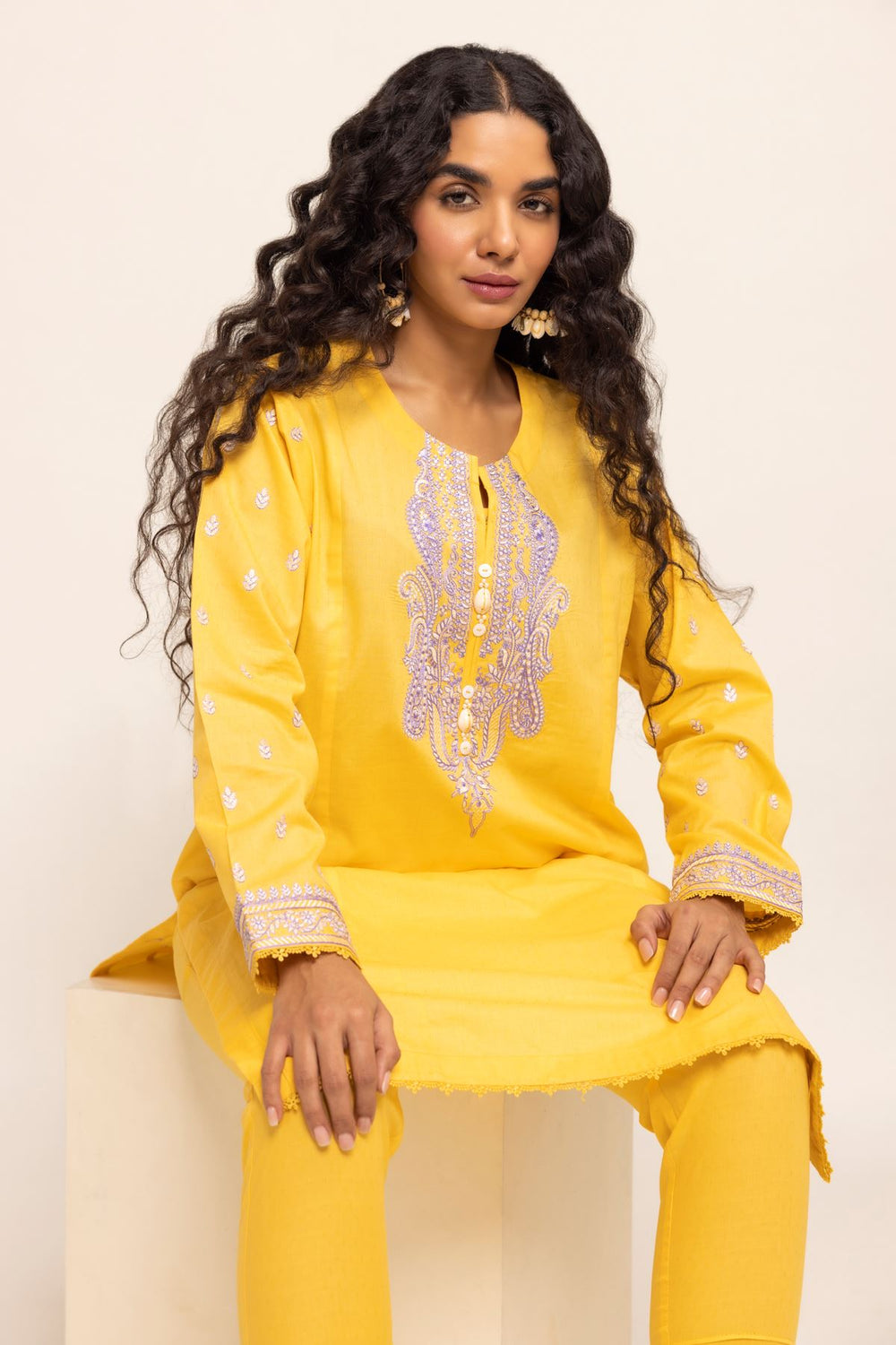 Authentic Pakistani Clothes Online a woman sitting on top of a white block