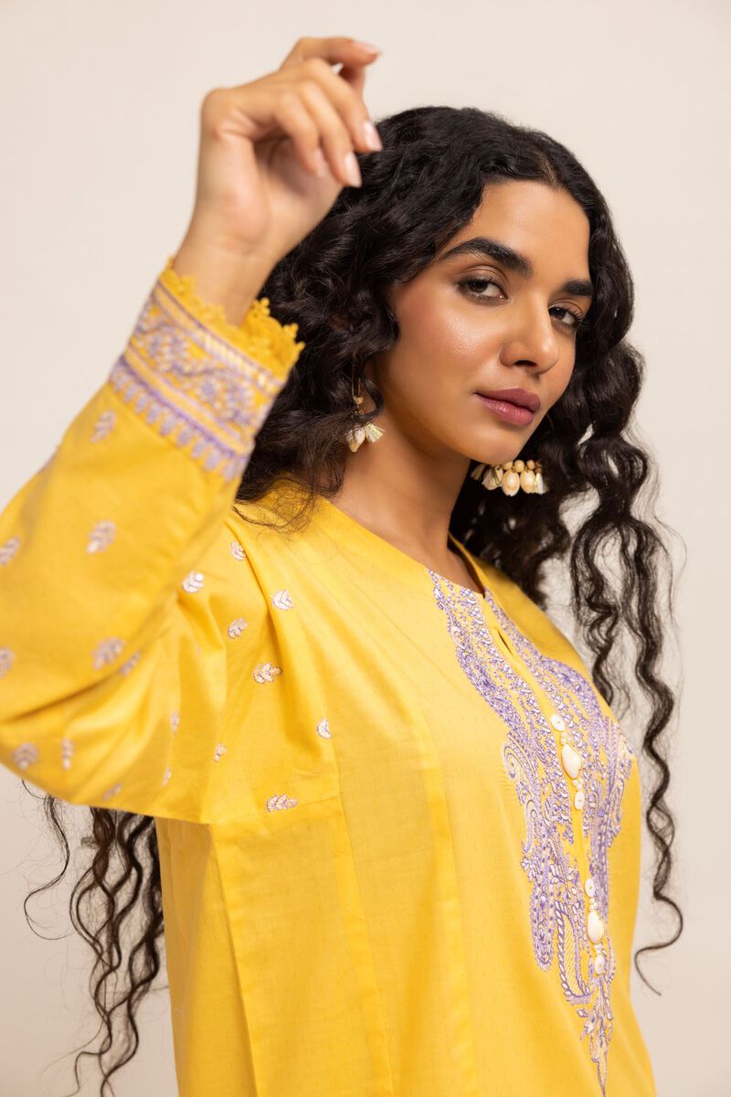 Authentic Pakistani Clothes Online a woman in a yellow dress with long curly hair