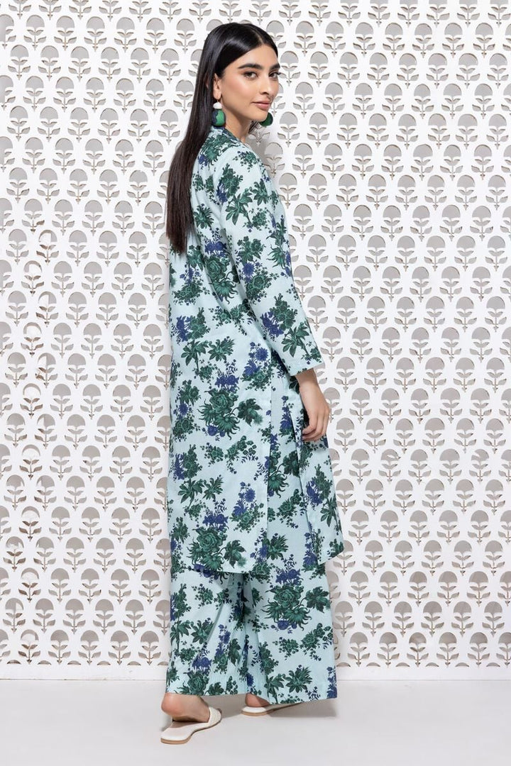 a khaadi  woman standing in front of a wall with a pattern on it