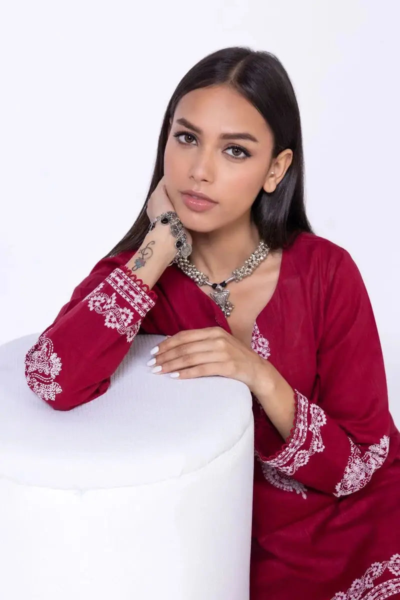 Close-up of KHAADI 2P EET24701A red shirt showcasing detailed white embroidery on the sleeves and neckline, paired with statement jewelry.