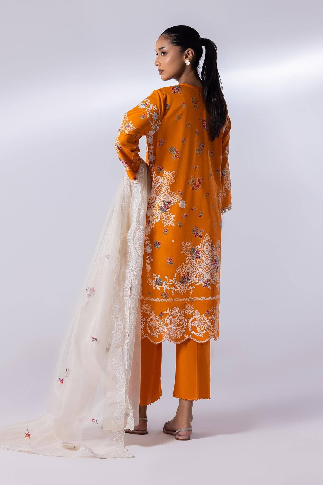 Back view of SANA SAFINA 3 Piece Lawn Suit in orange with intricate embroidery, paired with culottes and a white embroidered dupatta. Elegant ethnic outfit.