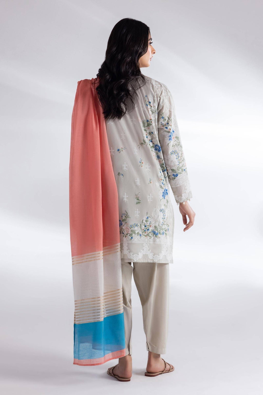 Back view of SANA SAFINAZ 3 Piece Muzlin Lawn Suit with floral print shirt, beige pants, and coral chiffon dupatta with blue border for a graceful look.
