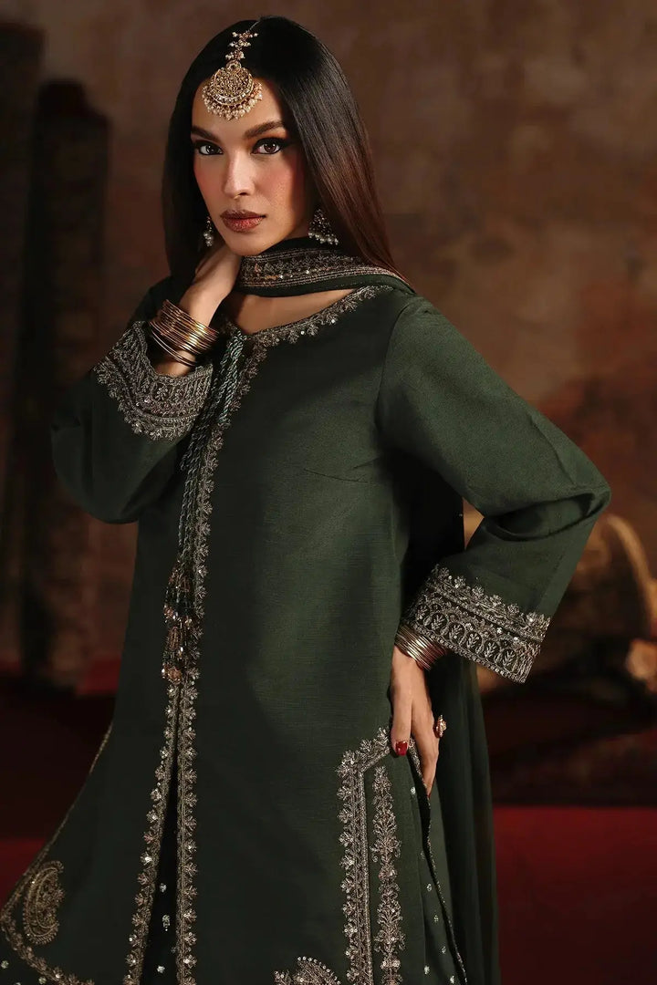 Model wearing deep emerald green embroidered raw-silk suit with silver detailing, paired with traditional jewelry, showcasing the luxurious fabric and craftsmanship