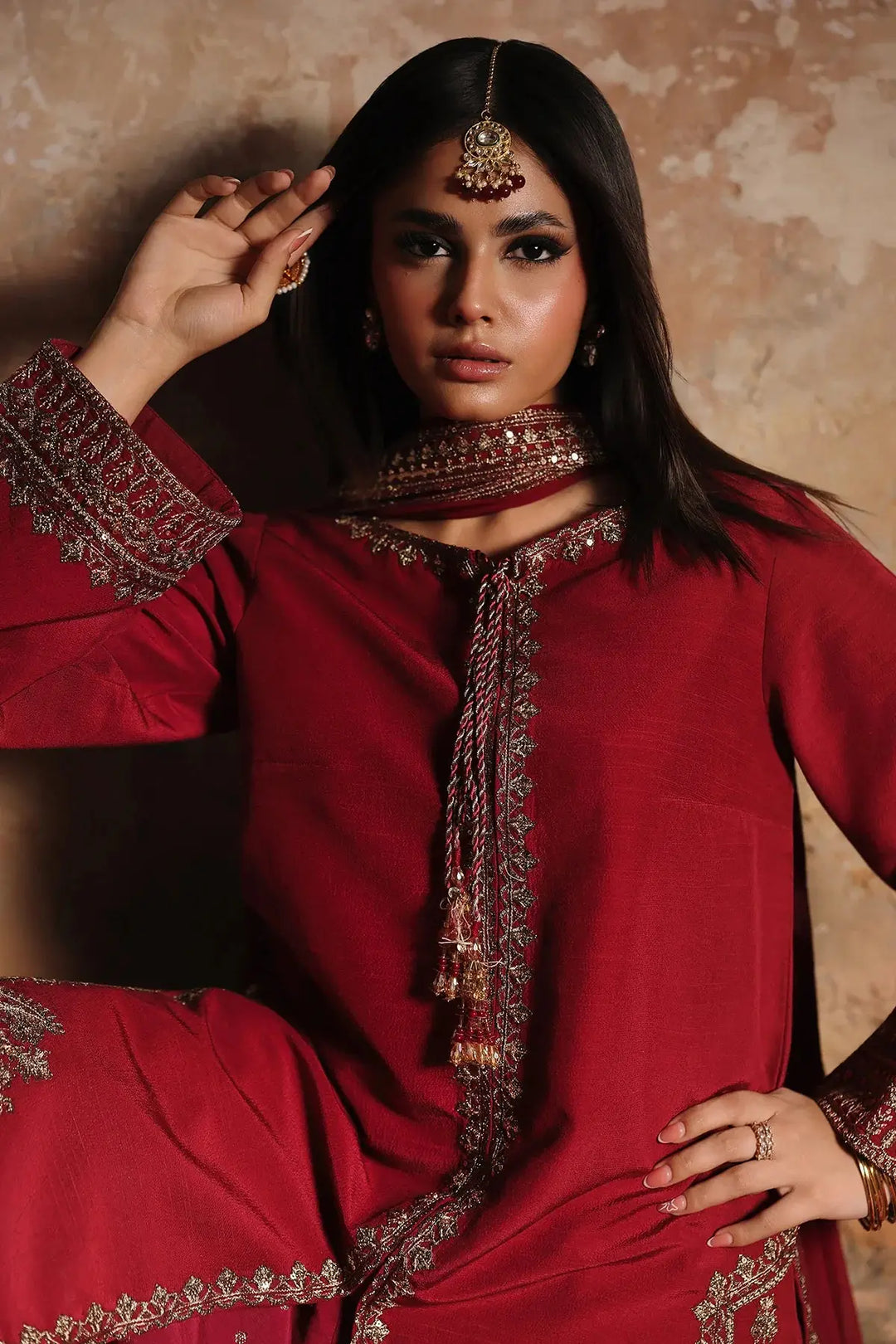 Red embroidered raw-silk suit with intricate gold embellishments, traditional jewelry, and matching accessories